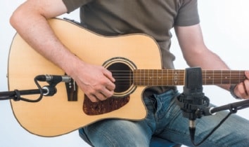 Mann spielt Gitarre vor Mikrofon